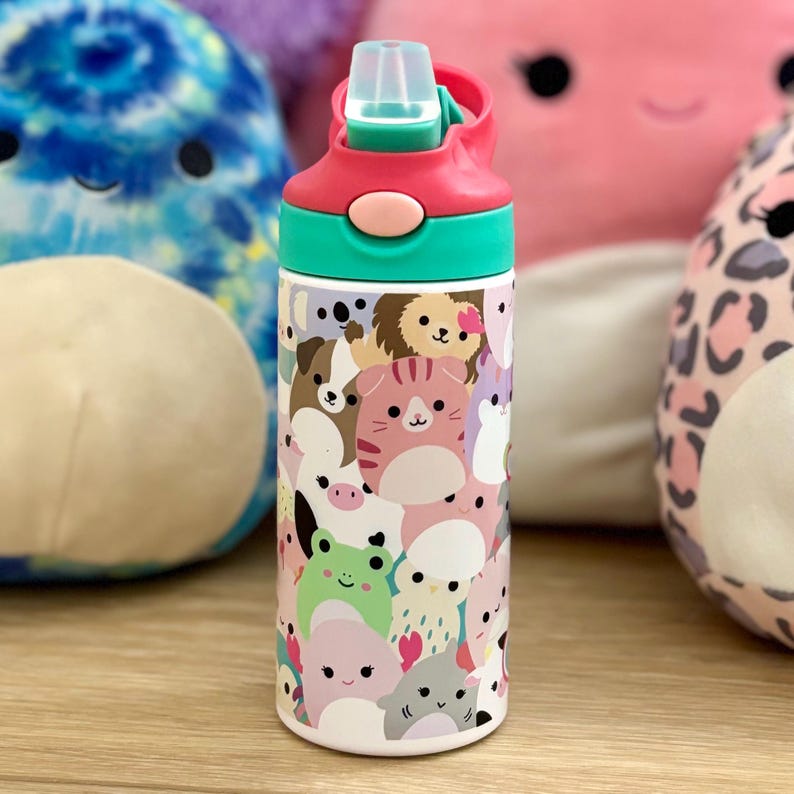Puede incluir: Una botella de agua de acero inoxidable con una tapa rosa y verde y un estampado colorido de animales de dibujos animados. La botella est&aacute; rodeada de peluches.