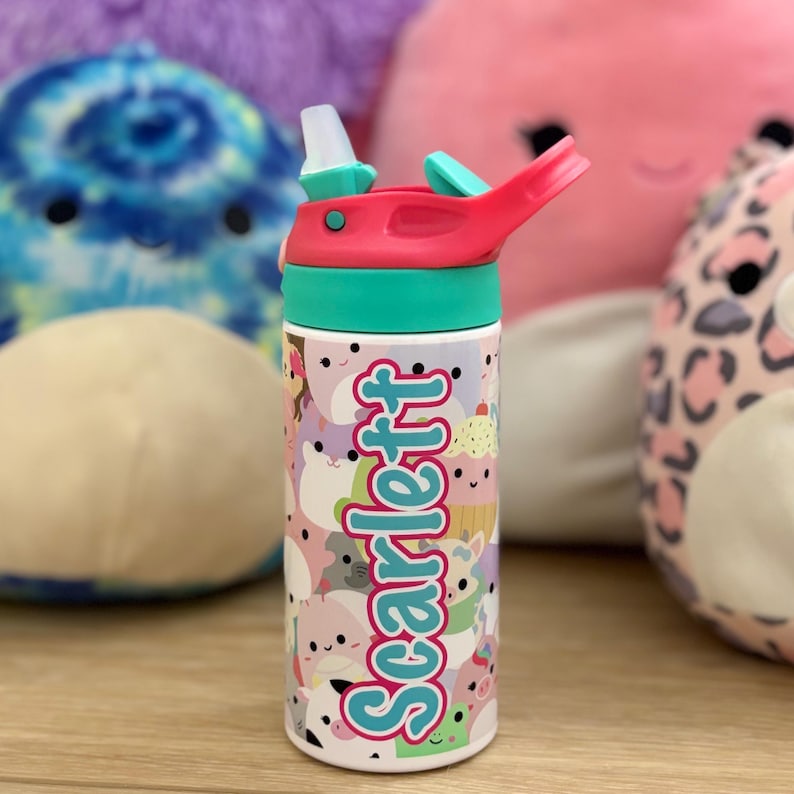 Puede incluir: Una botella de agua de color turquesa y rosa con una tapa de paja y un dise&ntilde;o colorido con animales de dibujos animados y el nombre "Scarlett" en letras turquesa.