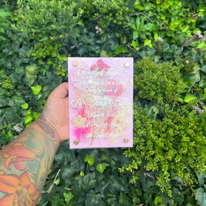 May include: A pink acrylic sign with a floral design and the text "Twenty Three", "Please join us for a Tea Party in honour of La' Charie Curtis", "August 19, 2022", "At One O'Clock", "The Ginger Room".