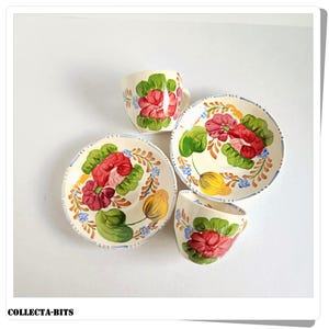 Puede incluir: Un juego de dos tazas de té y platillos florales vintage. Las tazas y los platillos son blancos con un diseño floral pintado a mano en tonos rojos, amarillos, verdes y azules.