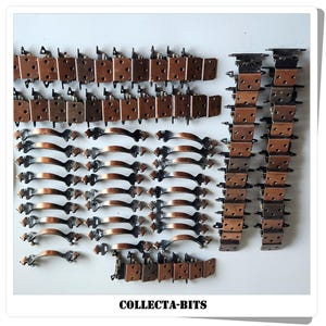 Könnte beinhalten: Eine Auswahl an Vintage-Schrankbeschlägen, darunter kupferfarbene Scharniere, Griffe und Eckwinkel. Die Griffe haben ein geschwungenes Design mit dekorativen Enden. Der Text "COLLECTA-BITS" ist ebenfalls im Bild enthalten.