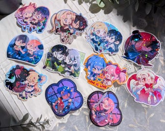 May include: A collection of eleven holographic stickers featuring various anime-style character pairs in chibi proportions. The designs include diverse colour palettes, dynamic poses, and one sticker with the text Love Is Love and a rainbow heart.