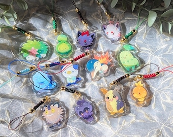 May include: A collection of 12 colorful anime character charms on clear plastic keychains. The charms feature various characters with different expressions and poses. The keychains are attached to colorful cords.