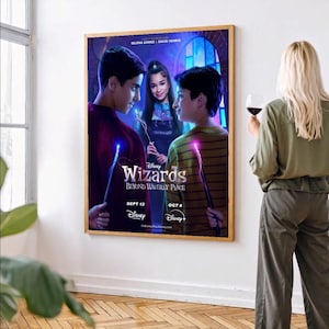 以下が含まれることがあります： セレーナ・ゴメスとデビッド・ヘンリーが出演する「Wizards Beyond Waverly Place」の額入りポスター。ポスターには、光る先端を持つ杖を持った3人の若者が描かれています。ポスターは白い壁に掛けられています。