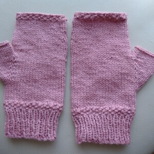 May include: A pair of pink knitted fingerless gloves with a ribbed cuff.