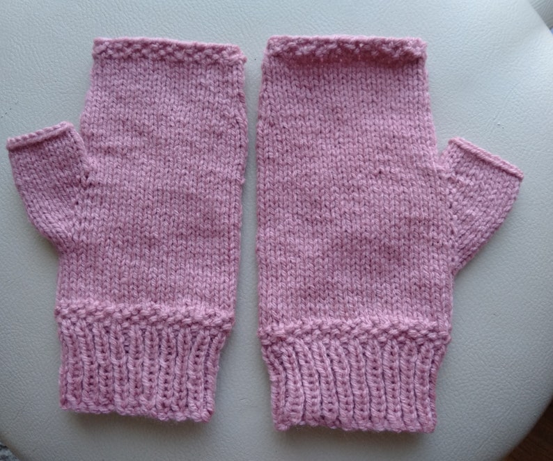 May include: A pair of pink knitted fingerless gloves with a ribbed cuff.