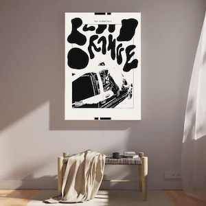 May include: A monochrome art print titled "The Essentials" on a grey wall. The print features abstract shapes and text. A bench with a blanket is below. A white curtain and a decorative bird are also visible.