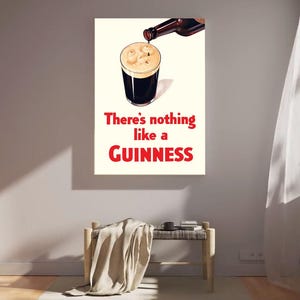 Puede incluir: Un cuadro enmarcado que muestra una pinta de Guinness que se est&aacute; sirviendo. El texto "There's nothing like a Guinness" est&aacute; en rojo. La obra de arte est&aacute; colgada en una pared sobre un banco.