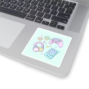 May include: A sticker featuring a pastel-colored gaming theme. The design includes a pink game controller, headphones, a handheld game console, and mushrooms. The sticker is on a laptop.