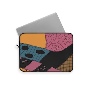 Peut inclure: Housse d'ordinateur portable avec un motif patchwork orange, bleu, rose et noir. La housse a une fermeture éclair et un ordinateur portable gris est partiellement visible à l'intérieur. Le motif comprend des détails cousus et un motif tourbillon.