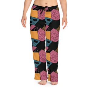 Könnte beinhalten: Bunte Schlafanzughose mit Patchwork-Design. Die Hose hat einen Kordelzug in der Taille und eine Mischung aus orangefarbenen, schwarzen, rosa, blauen und braunen Flicken. Das Design umfasst Spiral- und ovale Formen.