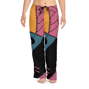 Peut inclure: Un pantalon de pyjama avec un motif patchwork jaune, rose, bleu et noir. Le pantalon a une taille avec cordon de serrage et un motif cousu, ressemblant à une tenue de personnage. Ce pantalon confortable est idéal pour se détendre ou dormir.