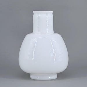 May include: A white, opaque glass vase with a bulbous body and a cylindrical neck. The vase has a smooth, glossy finish and sits on a small, circular base. The overall shape is reminiscent of a gourd.