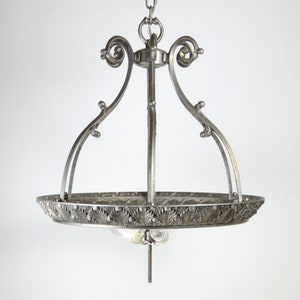 May include: A silver chandelier with a decorative, ornate design. The chandelier has a circular, open-work base and four curved arms.