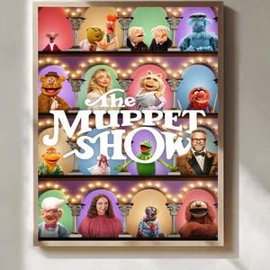 Könnte beinhalten: Ein gerahmtes Poster mit dem Logo der Muppet Show und verschiedenen Muppet-Charakteren. Das Poster hat einen beigen Rahmen und zeigt die Charaktere in einem mehrstufigen Design mit dekorativen Lichtern. Zu den Muppets gehören Kermit der Frosch, Miss Piggy und Fozzie Bär.