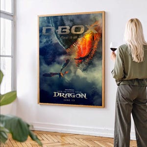 Könnte beinhalten: Ein gerahmtes Filmplakat für "Drachenzähmen leicht gemacht" mit einer Drachenillustration. Das Plakat trägt den Text "D-BOX" und "Feel it all". Das Plakat befindet sich in einem Holzrahmen.