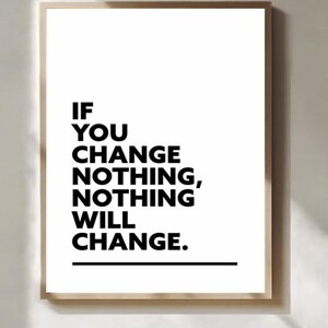May include: A framed print with a white background and black text that reads: "IF YOU CHANGE NOTHING, NOTHING WILL CHANGE." The frame is a light brown colour. The print is a motivational piece.