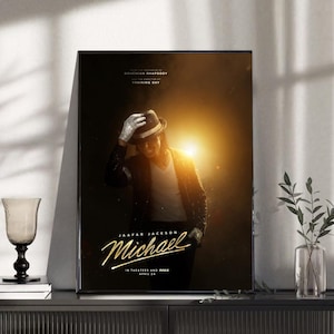 Könnte beinhalten: Gerahmtes Poster mit einem stilisierten Bild von Michael Jackson in schwarzer Jacke, Hut und Handschuhen. Das Poster trägt den Titel "Michael" in goldener Schrift, mit zusätzlichem Text darunter. Der Hintergrund ist dunkel mit hellem Licht.