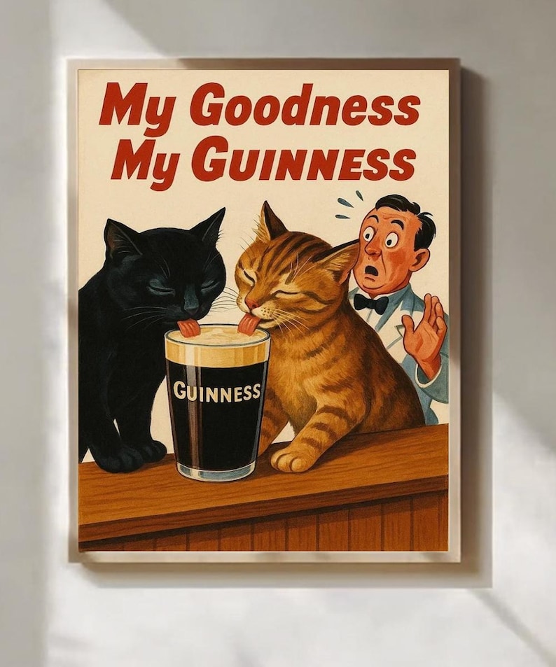 May include: A framed vintage-style print featuring two cats licking a pint of Guinness, with a surprised bartender. The text "My Goodness My Guinness" is displayed in red. The black cat and the tabby cat are the focal point.