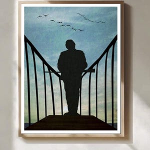 May include: Framed art print depicting a silhouette of a person on a wooden structure, gazing at a blue sky with birds in flight. The artwork has a minimalist style, creating a serene and contemplative atmosphere.