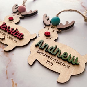May include: Two wooden reindeer ornaments with the names "Jessica" and "Andrew" and the text "Baby's First Christmas" and the year "2022".