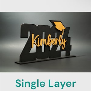 May include: Black wooden 2024 graduation sign with a gold graduation cap and the name Kimberly. The sign is on a white background.