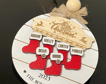 May include: A personalized Christmas ornament with a white background and red stockings. The ornament features the names Adrian, Holley, Bella, Birdie, Carter, and Parker. The text "Merry Christmas" is engraved on a wooden accent, along with the year 2025 and the family name.