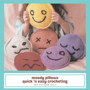 May include: A selection of crocheted round pillows in various colours, each with a different facial expression. The pillows include yellow, orange, white, red, and purple. The text at the bottom reads "moody pillows quick 'n easy crocheting - PDF PATTERN ONLY -"