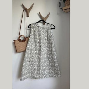 May include: A sleeveless gray dress with a white dalmatian print. The dress has a round neckline and a loose fit.