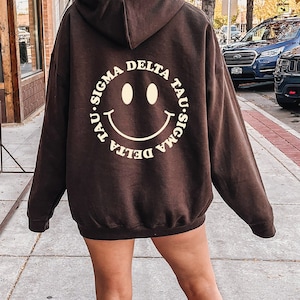 Sigma Delta Tau Smiley Sorority Sweatshirt | Trendy Sig Delt Custom Sorority Hoodie | Available in Brown Black Green Blue & Pink