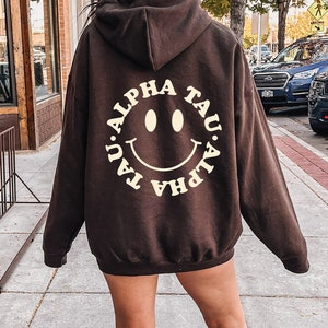 Alpha Sigma Tau Smiley Sorority Sweatshirt | Trendy Alpha Tau Custom Sorority Hoodie | Available in Brown Black Green Blue & Pi