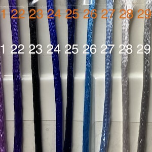 May include: A close-up of a selection of embroidery floss spools, numbered 20 through 30. The floss colors range from pink to light gray.