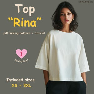 Può includere: Una donna indossa un top bianco a maniche corte. L'immagine include il testo "Top 'Rina' modello di cucito pdf + tutorial" e "Taglie incluse XS - 3XL". È visibile anche un cuore rosa con il numero 1 e le parole "Livello di cucito".