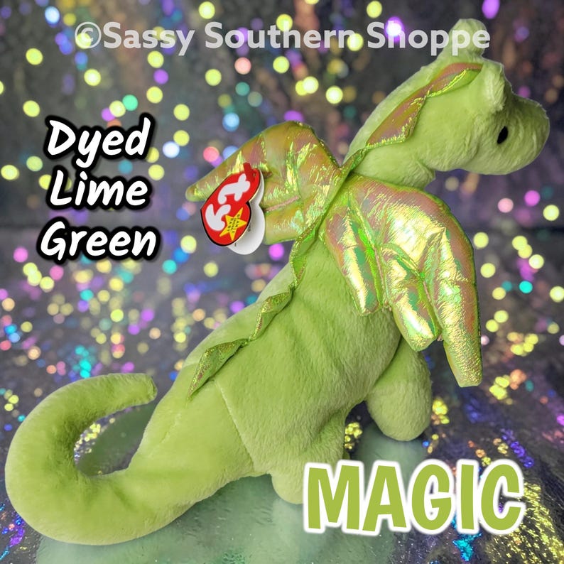 May include: A lime green plush dragon toy with iridescent wings and a red heart-shaped tag attached to its neck. The text Dyed Lime Green and MAGIC are visible on the image, along with the copyright text Sassy Southern Shoppe.