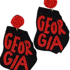 May include: A pair of black and red beaded earrings shaped like the state of Georgia with the word "GEORGIA" spelled out in red beads.