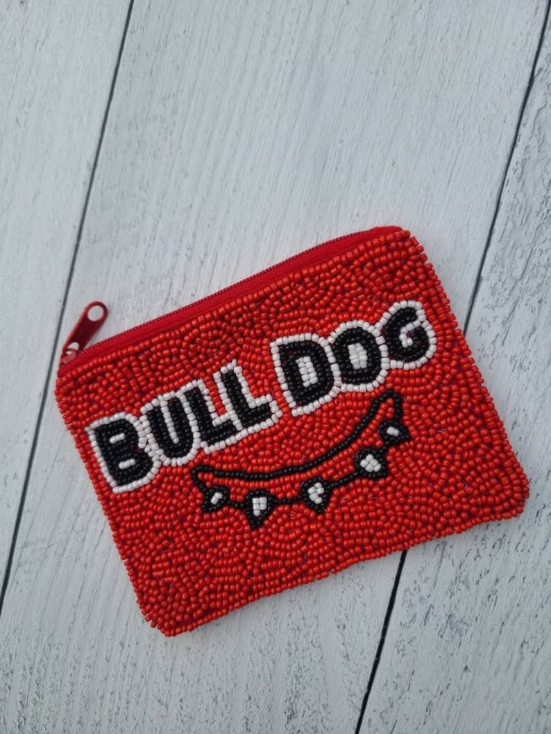 Pu&ograve; includere: Portamonete rosso a perline con un designo "BULLDOG" bianco e nero e un collare a perline nere con denti bianchi.