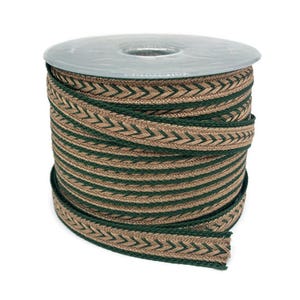 Puede incluir: Un rollo de cinta decorativa con un patrón de chevrón repetido en verde y marrón. La cinta está enrollada en una bobina de plástico transparente, ideal para manualidades o adornos. La cinta tiene una textura tejida.