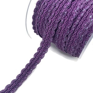 May include: Purple braided trim with a shimmery finish. The trim is wound around a spool.