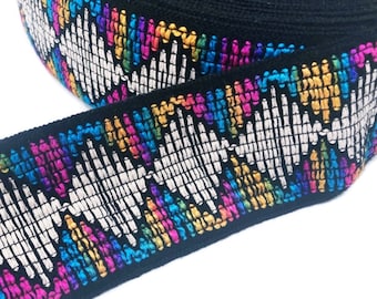 May include: Black woven trim with a colorful geometric pattern. The trim features a white, silver, and black design with accents of pink, blue, yellow, green, and orange.