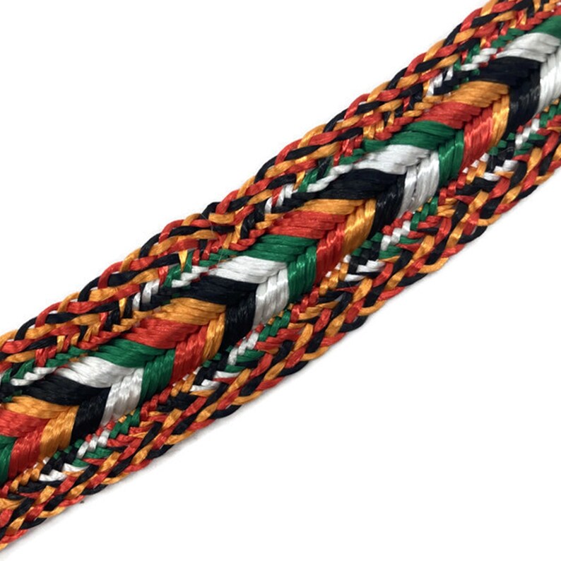 May include: A braided trim with a multi-colored pattern of black, white, red, green, and gold. The trim is woven in a herringbone pattern.