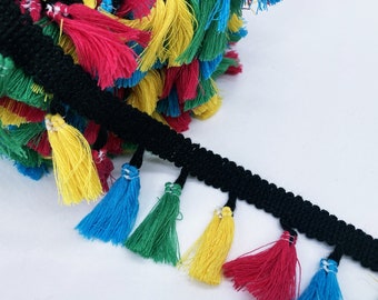 Op de afbeelding: Zwarte bies met kleurrijke kwastjes. De kwastjes zijn blauw, groen, geel en rood.