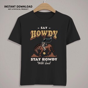 K&ouml;nnte beinhalten: Schwarzes T-Shirt mit einer Vintage-Illustration eines Cowboys, der ein Pferd reitet und ein Lasso wirft. Der Text "Say Howdy Stay Rowdy Wild Soul" ist auf dem T-Shirt aufgedruckt.