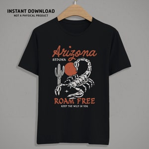 May include: Black t-shirt with a desert-themed graphic. The design features a scorpion, a cactus, and the words "Arizona Sedona" and "Roam Free Keep the Wild in You" in a vintage style. "Instant Download Not a Physical Product" is printed at the top.