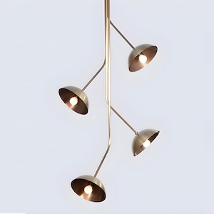 Puede incluir: Una lámpara colgante moderna, en tono latón, con cuatro pantallas en forma de cuenco, cada una con una bombilla. El diseño presenta brazos curvos que se extienden desde un tallo central, creando un aspecto contemporáneo.
