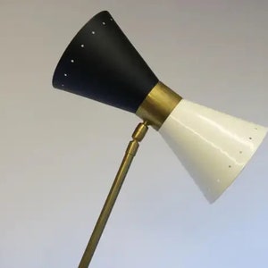May include: A black and white adjustable floor lamp with a brass stem and a cone-shaped shade. The shade has a pattern of small holes.