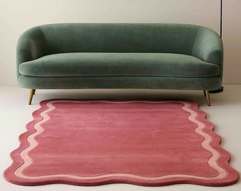 May include: A modern living room setup featuring a green velvet sofa with gold legs, a pink scalloped rug, and a black and white framed artwork. A black floor lamp with a white globe shade provides soft lighting.