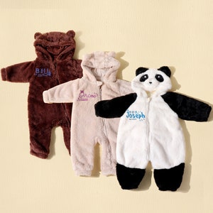 May include: Three plush baby onesies in brown, tan, and white with attached hoods. The brown onesie has bear ears and the name "Bell" embroidered in blue. The tan onesie has the name "Chloe" embroidered in purple. The white onesie is designed as a panda with the name "Joseph" in blue.