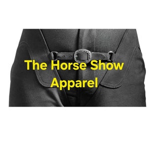May include: Black riding breeches with a leather belt and silver buckle. The text "The Horse Show Apparel" is printed in yellow on the front of the breeches.