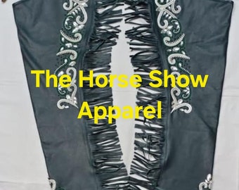 May include: Black leather chaps with fringe and green and white embroidery. The chaps have the text "The Horse Show Apparel" on them.