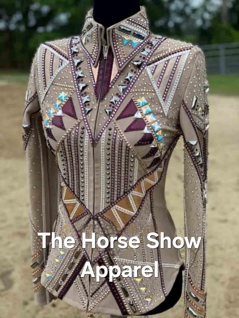 May include: A beige show jacket with a geometric design featuring brown, purple, and silver accents. The jacket is embellished with rhinestones and has a zipper closure. The text "The Horse Show Apparel" is printed on the front of the jacket.